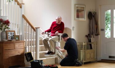 Ο ηλικιωμένος άνδρας κάθισε χαρούμενος στο αναπηρικό καροτσάκι του, ενώ ο τεχνικός ολοκλήρωνε την εγκατάστασή του.